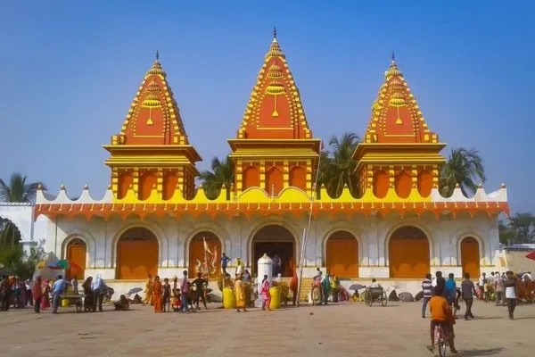 Tourists and devotees standing or praying in front of the temple.